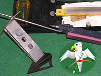 Lansky-Set: Eine schraubstockartige Klemme hält die Klinge und vorgegebene Löcher, für die an den Schleifsteinen anzubringende Führungsstange, dienen dem Einhalten des Schleifwinkels. Nur etwas für kurze Klingen.    © Falk 2006